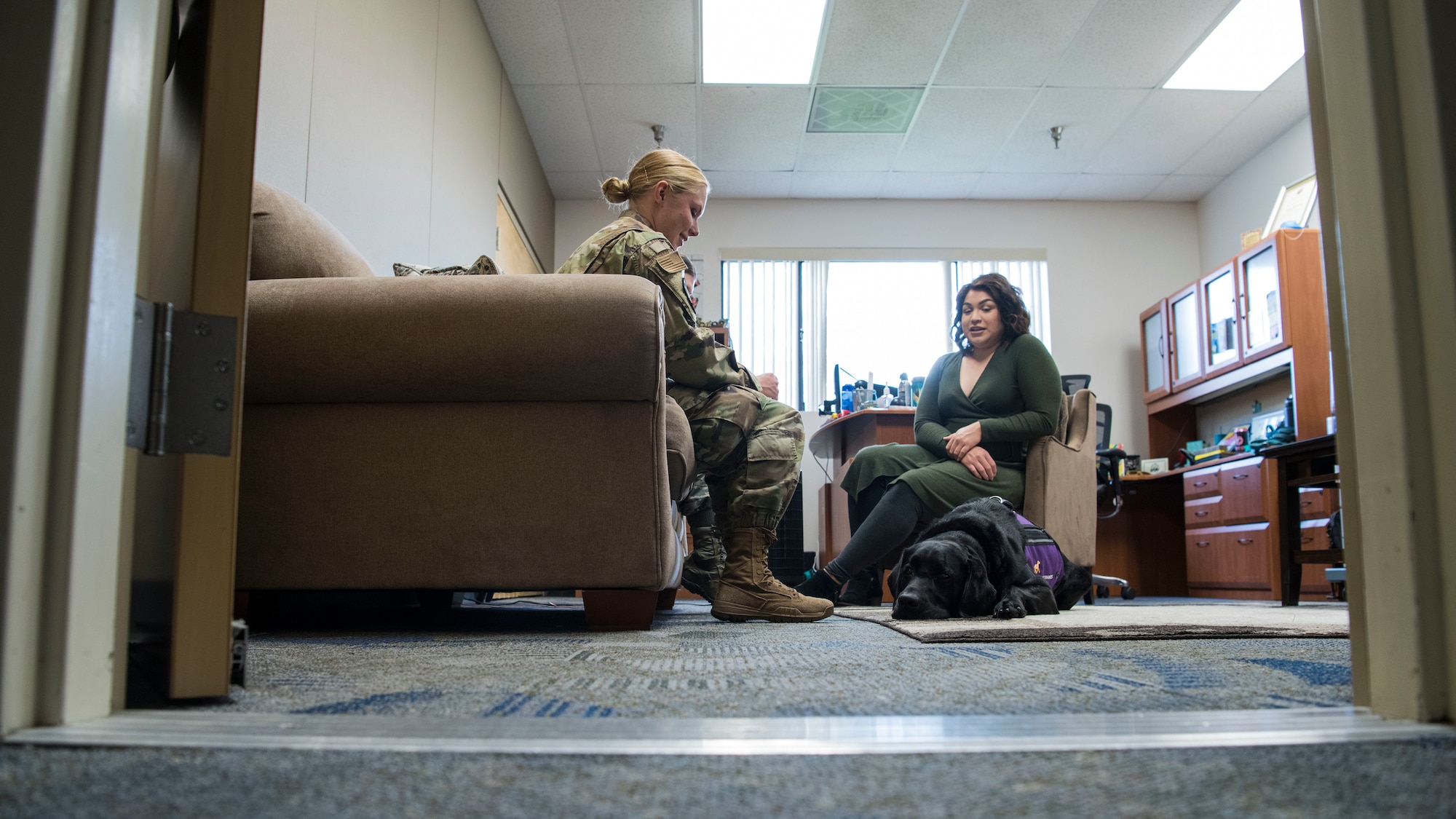 Teresa Loya, 30th Space Wing sexual assault prevention and response specialist, and Preston, 30th SW courthouse facility dog, meet with an Airman at Vandenberg Air Force Base, Calif., Dec. 4, 2019. Preston comes to work every day to the Sexual Assault Prevention and Response office, as he is a certified and highly trained courthouse dog who provides support to victims and witnesses. (U.S. Air Force photo by Airman 1st Class Aubree Milks)
