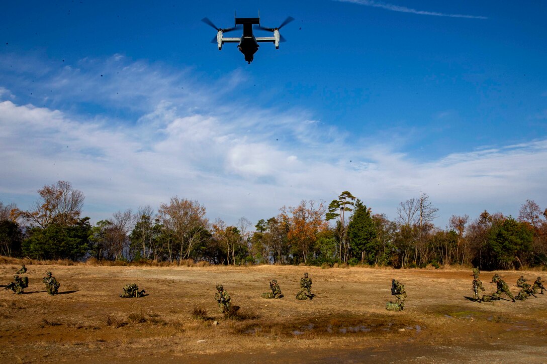 A group of Marines run underneath a military aircraft.