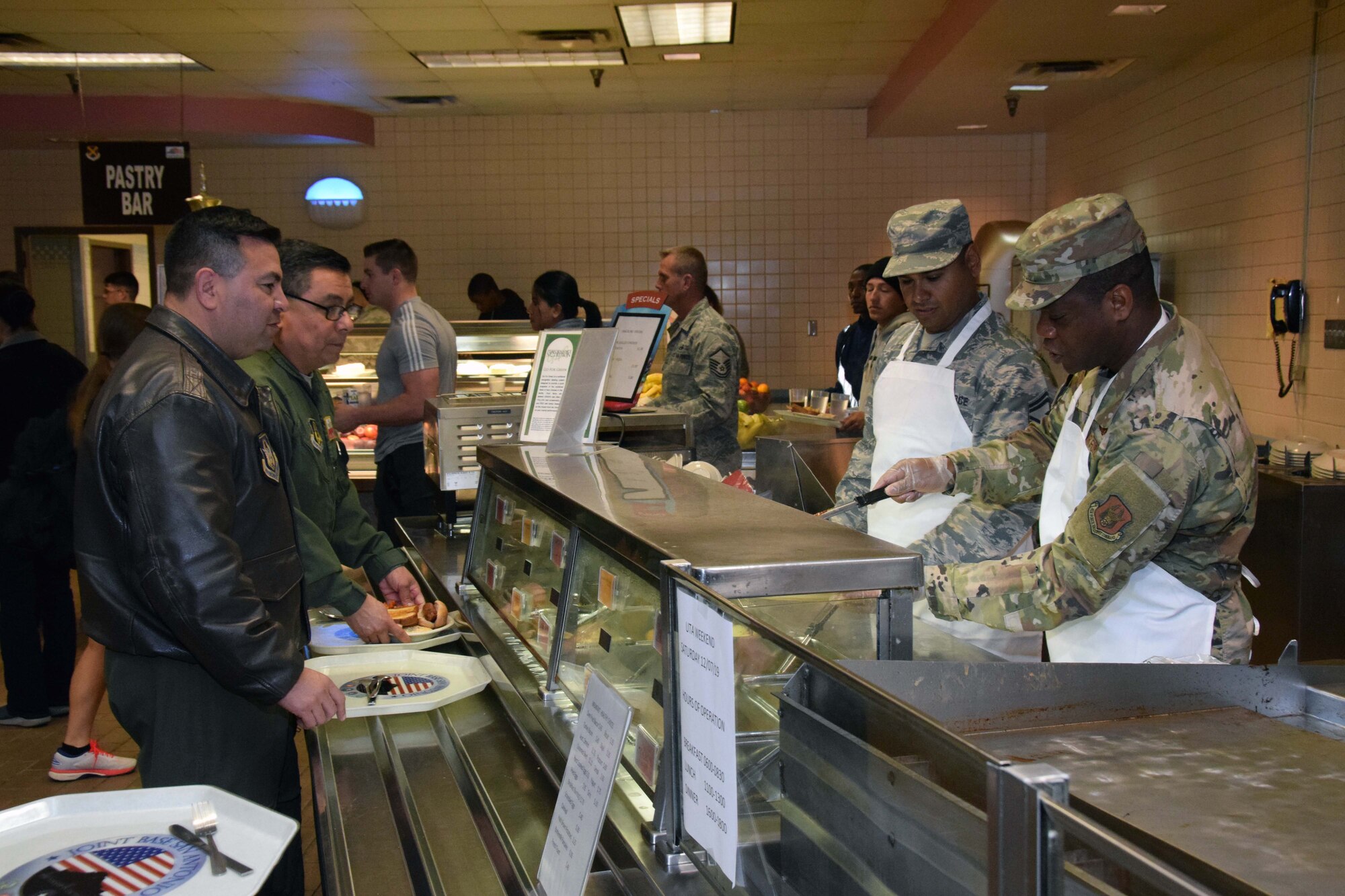 Senior Master Sgt. Marc A. Flores, 433rd Aircraft Maintenance Squadron first sergeant, and Chief Master Sgt. Troy A. Pearson, 433rd AMXS superintendent, plate meals at the Serve the Airmen event Dec. 7, 2019 at the Live Oak Dining Facility on Joint Base San Antonio-Lackland, Texas.