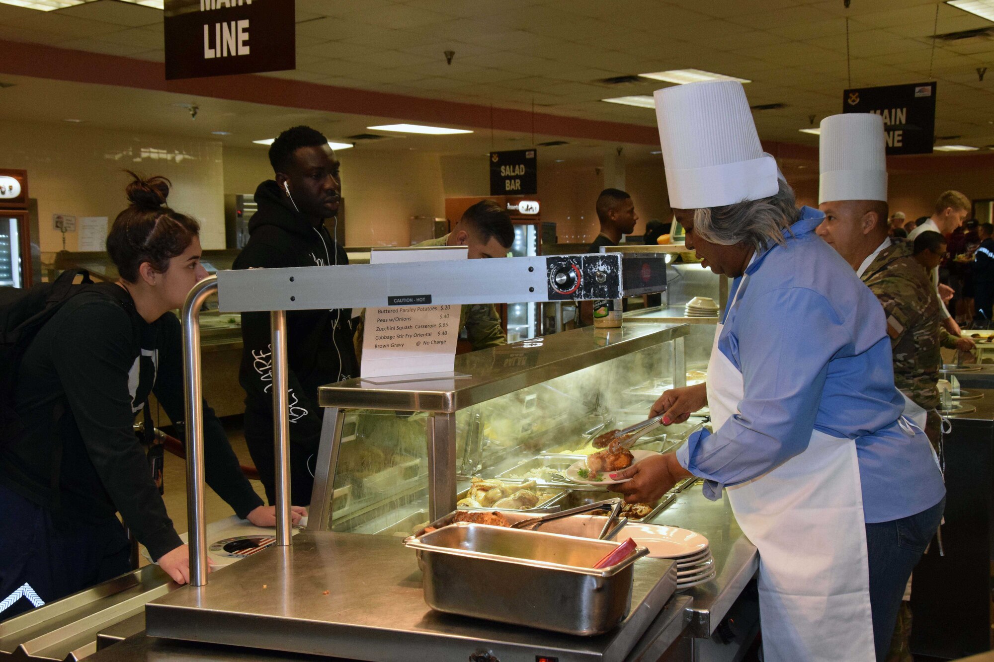 Honorary commander Barbara Gervin-Hawkins, Texas Representative, District 120, and Chief Master Sgt. Miguel A. Casso, 356th Airlift Squadron chief loadmaster, plate meals at the Serve the Airmen event Dec. 7, 2019 at the Live Oak Dining Facility on Joint Base San Antonio-Lackland, Texas.