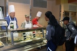 Honorary commander John Thurman, Heart of Texas Realty owner, Chief Master Sgt. Shana C. Cullum, 433rd Airlift Wing command chief, and Craig Veltri, Veltri Interests Inc. founder, plate meals at the Serve the Airmen event Dec. 7, 2019 at the Live Oak Dining Facility on Joint Base San Antonio-Lackland, Texas.