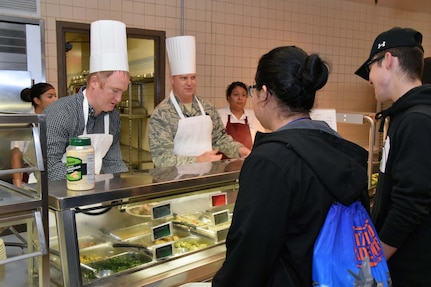 Honorary commander ; Rich Weimert, San Antonio Missions Baseball director of baseball operations, and Lt. Col. Michael T. Webb, 433rd Aircraft Maintenance Squadron commander, plate meals at the Serve the Airmen event Dec. 7, 2019 at the Live Oak Dining Facility on Joint Base San Antonio-Lackland, Texas.