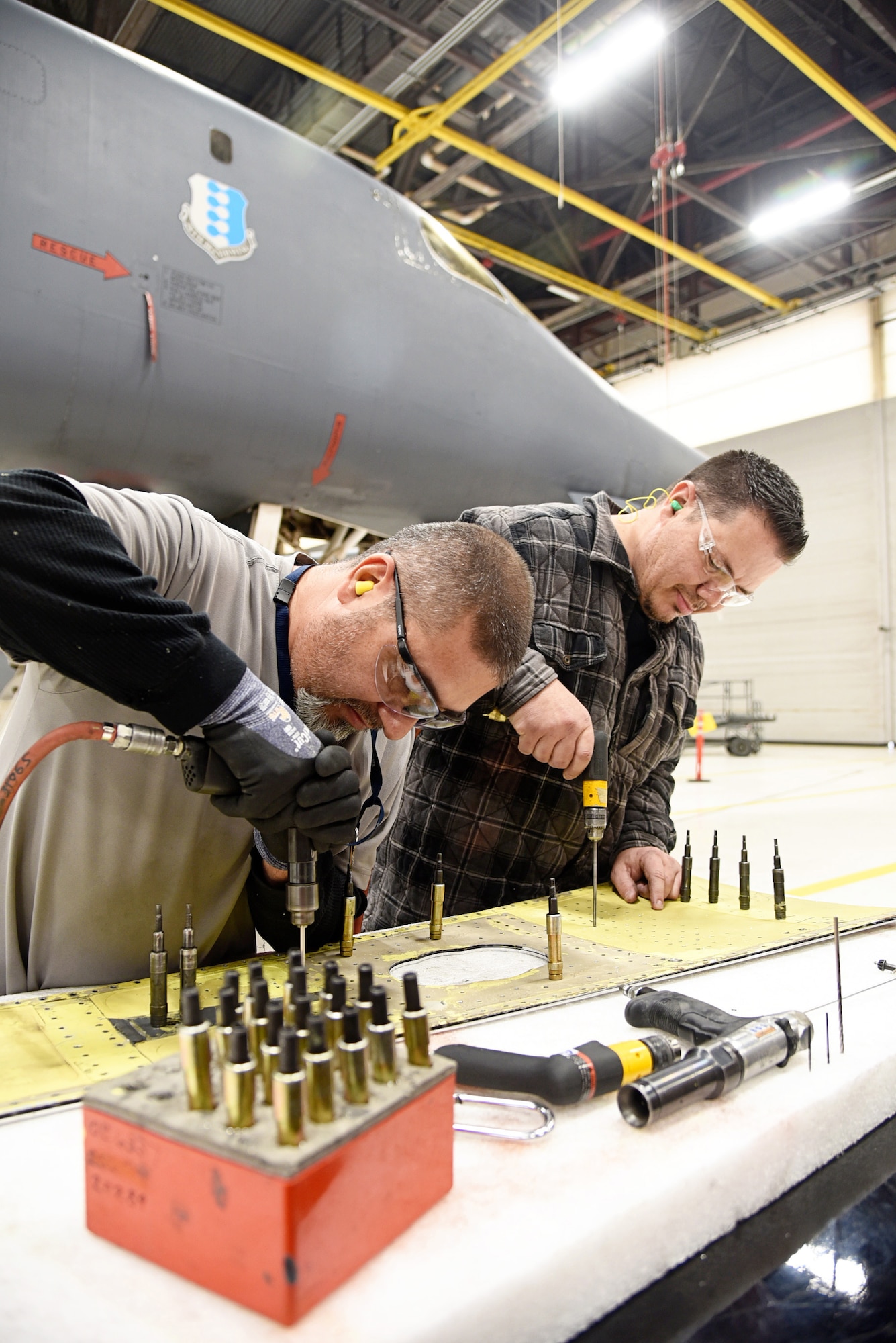 Angel Rodriguez and Terry Shadduck, sheet metal mechanics with the 567th Aircraft Maintenance Squadron, drill a skin splice for the forward intermediate fuselage of the B-1B Lancer. Urgent repairs to several of the B-1 fleet began in October, but ongoing maintenance to the aging aircraft is expected to keep the B-1 operationally functional until at least 2040. (U.S. Air Force photo/Kelly White)