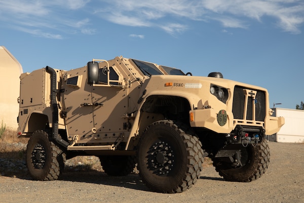 A military combat vehicle sits in a dirt lot.