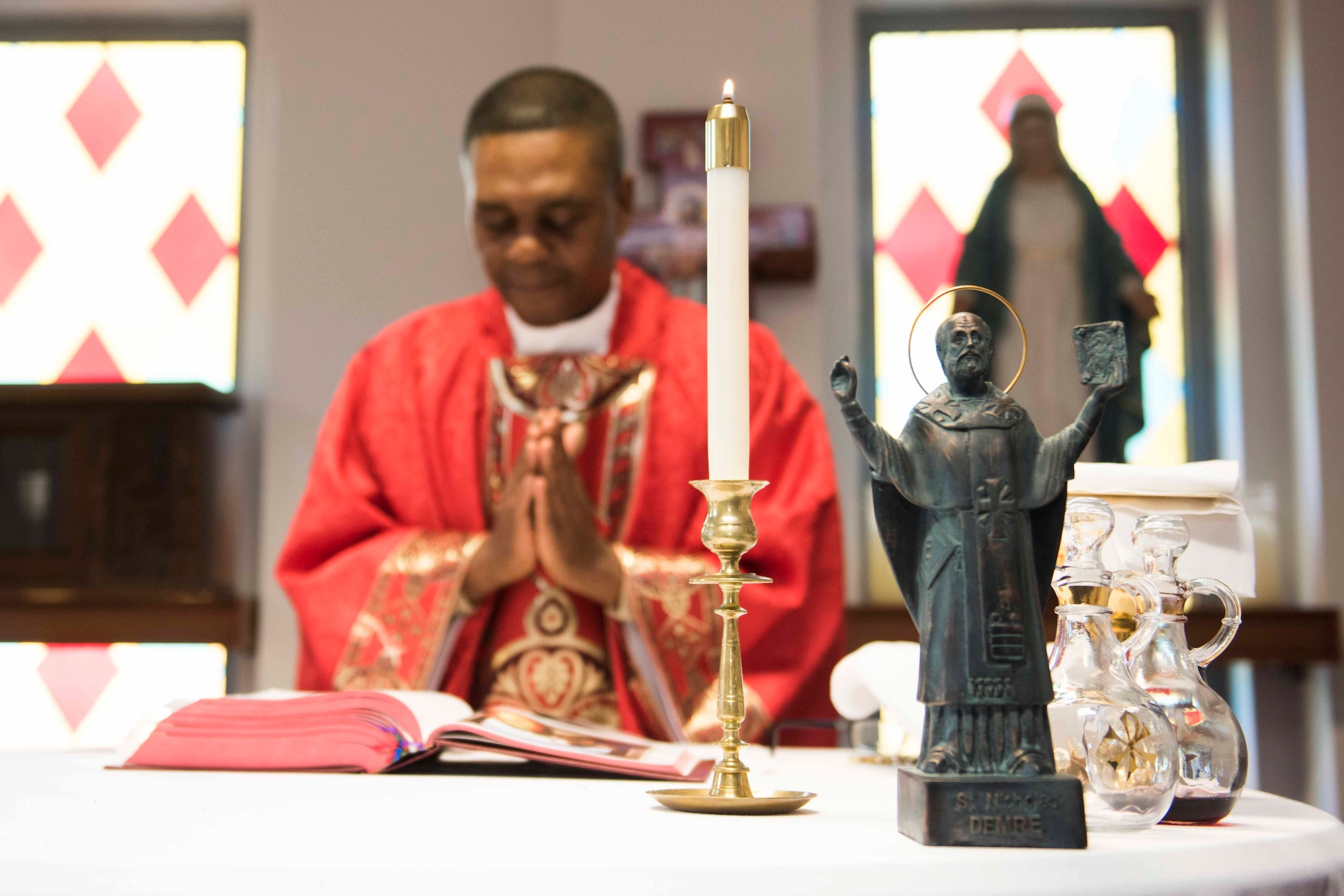 U.S. Air Force Maj. Paul Amaliri, 39th Air Base Wing deputy wing chaplain, celebrates a Catholic service in honor of St. Nicholas, whose statue stands on the altar Dec. 6, 2019, at Incirlik Air Base, Turkey. St. Nicholas served as a Christian bishop within the borders of modern-day Turkey and is the historical inspiration for the mythical Christmas figure, Santa Claus. (U.S. Air Force photo by Staff Sgt. Joshua Magbanua)
