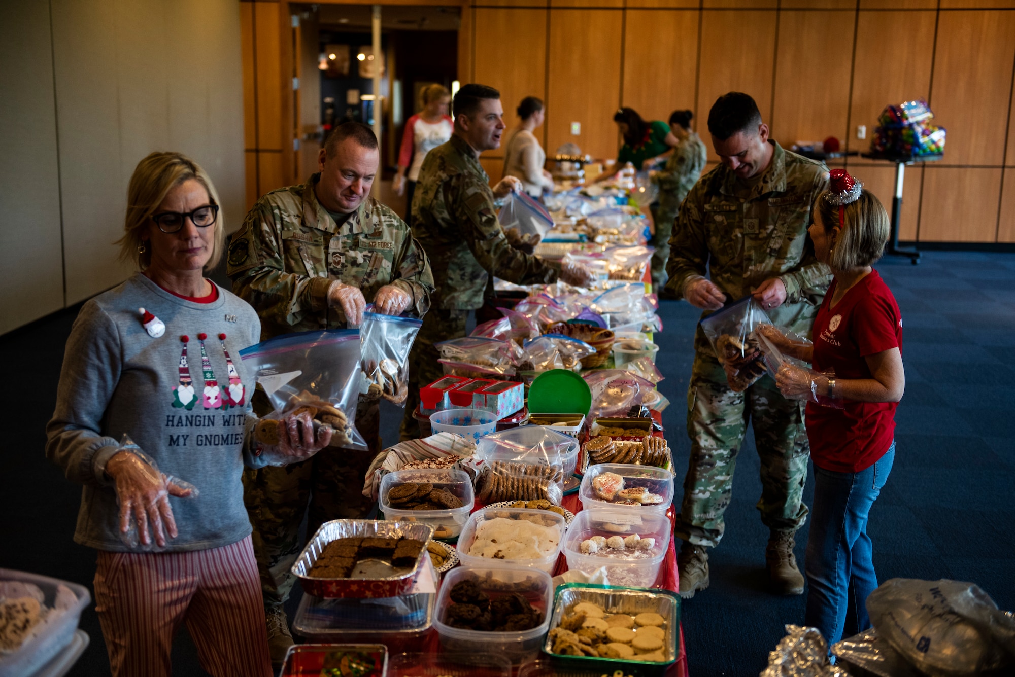 Airmen and first sergeants from the 325th Fighter Wing bag holiday cookies with members of the Tyndall Spouses Club at Tyndall Air Force Base, Florida, Dec. 9, 2019. The Tyndall Spouses Club and Tyndall First Sergeants held a Cookie Caper event, where they collected hundreds of donated cookies to distribute to Airmen living in the on base dormitories, as well as giving extra cookies to units and offices on base. The goal of the event was to take care of Airmen and to give back to those who serve the wing's mission. (U.S. Air Force photo by Staff Sgt. Magen M. Reeves)