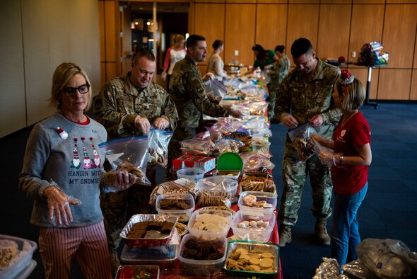 Airmen and first sergeants from the 325th Fighter Wing bag holiday cookies with members of the Tyndall Spouses Club at Tyndall Air Force Base, Florida, Dec. 9, 2019. The Tyndall Spouses Club and Tyndall First Sergeants held a Cookie Caper event, where they collected hundreds of donated cookies to distribute to Airmen living in the on base dormitories, as well as giving extra cookies to units and offices on base. The goal of the event was to take care of Airmen and to give back to those who serve the wing's mission. (U.S. Air Force photo by Staff Sgt. Magen M. Reeves)