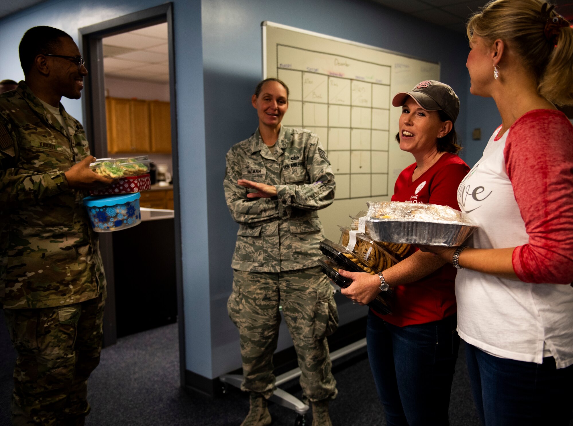 U.S. Air Force Tech. Sgts. Antawn Knight, left, and Jeannie Hartman, center, receive holiday cookies from Amy Beaulieu, and Samantha Laidlaw, members of the Tyndall Spouses club at Tyndall Air Force Base, Florida, Dec. 9, 2019. The Tyndall Spouses Club and Tyndall First Sergeants held a Cookie Caper event, where they collected hundreds of donated cookies to distribute to Airmen living in the on base dormitories, as well as giving extra cookies to units and offices on base. (U.S. Air Force photo by Staff Sgt. Magen M. Reeves)