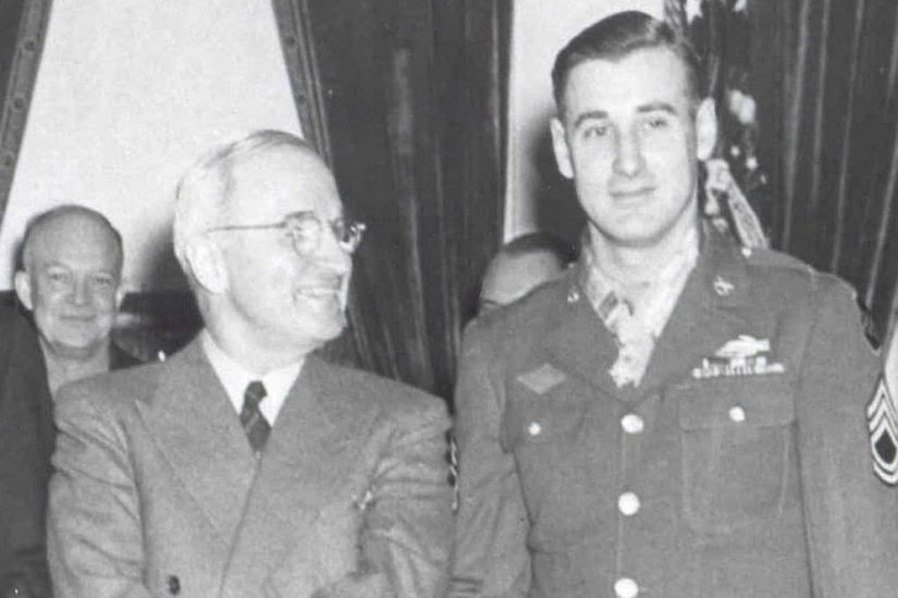President Harry S. Truman, left, stands next to  a soldier who is wearing the Medal of Honor around his neck. Army Gen. Dwight D. Eisenhower is smiling in the background.