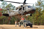 Two paratroopers from the 407th Brigade Support Battalion, 2nd Brigade Combat Team, 82nd Airborne Division, attach a Humvee by harness to the bottom of a UH-60 Black Hawk helicopter during sling load training on Nov. 17. Sling load is a technique used to quickly move supplies from one area to another by helicopter.