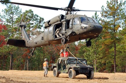 Two paratroopers from the 407th Brigade Support Battalion, 2nd Brigade Combat Team, 82nd Airborne Division, attach a Humvee by harness to the bottom of a UH-60 Black Hawk helicopter during sling load training on Nov. 17. Sling load is a technique used to quickly move supplies from one area to another by helicopter.