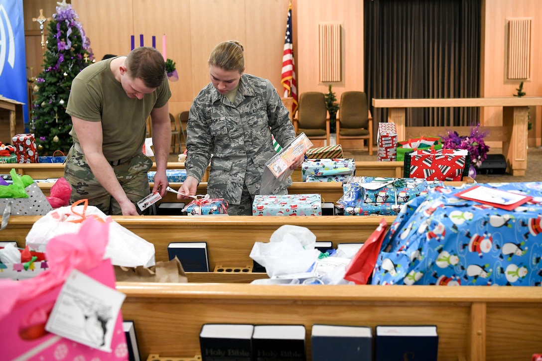 Volunteers sift through wrapped gifts situated on pews inside the base chapel.
