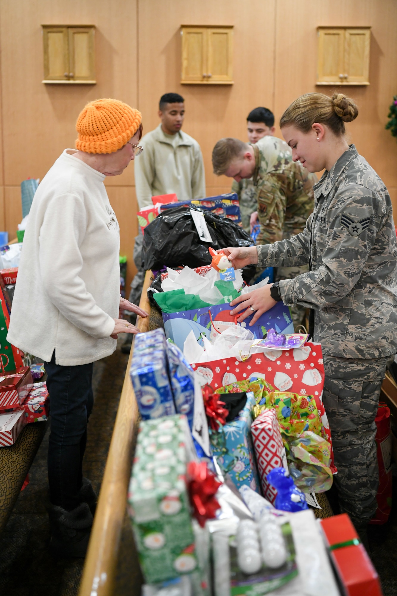 Volunteers sifting through wrapped gifts situated on a pew inside the base chapel.