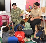 Petty Officer 2nd Class Angelica Brown (left), community service coordinator assigned to Navy Recruiting District San Antonio, joined by NRD-SA’s assistant command career counselor, Petty Officer 1st Class Kamitria Delaney, reads to a first-grade class at Dorie Miller Elementary School as part of the school’s annual Pearl Harbor and Dorie Miller Remembrance Program.