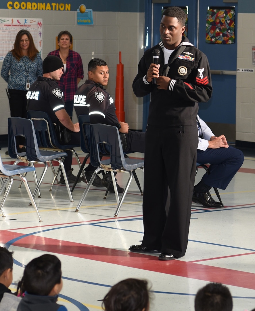 Petty Officer 1st Class Shomari Cooper, assigned to Navy Recruiting District San Antonio, speaks with students of Dorie Miller Elementary during the school’s annual Pearl Harbor and Dorie Miller Remembrance Program.  The event was held in remembrance of those who fought and for those who lost their lives Dec. 7, 1941.