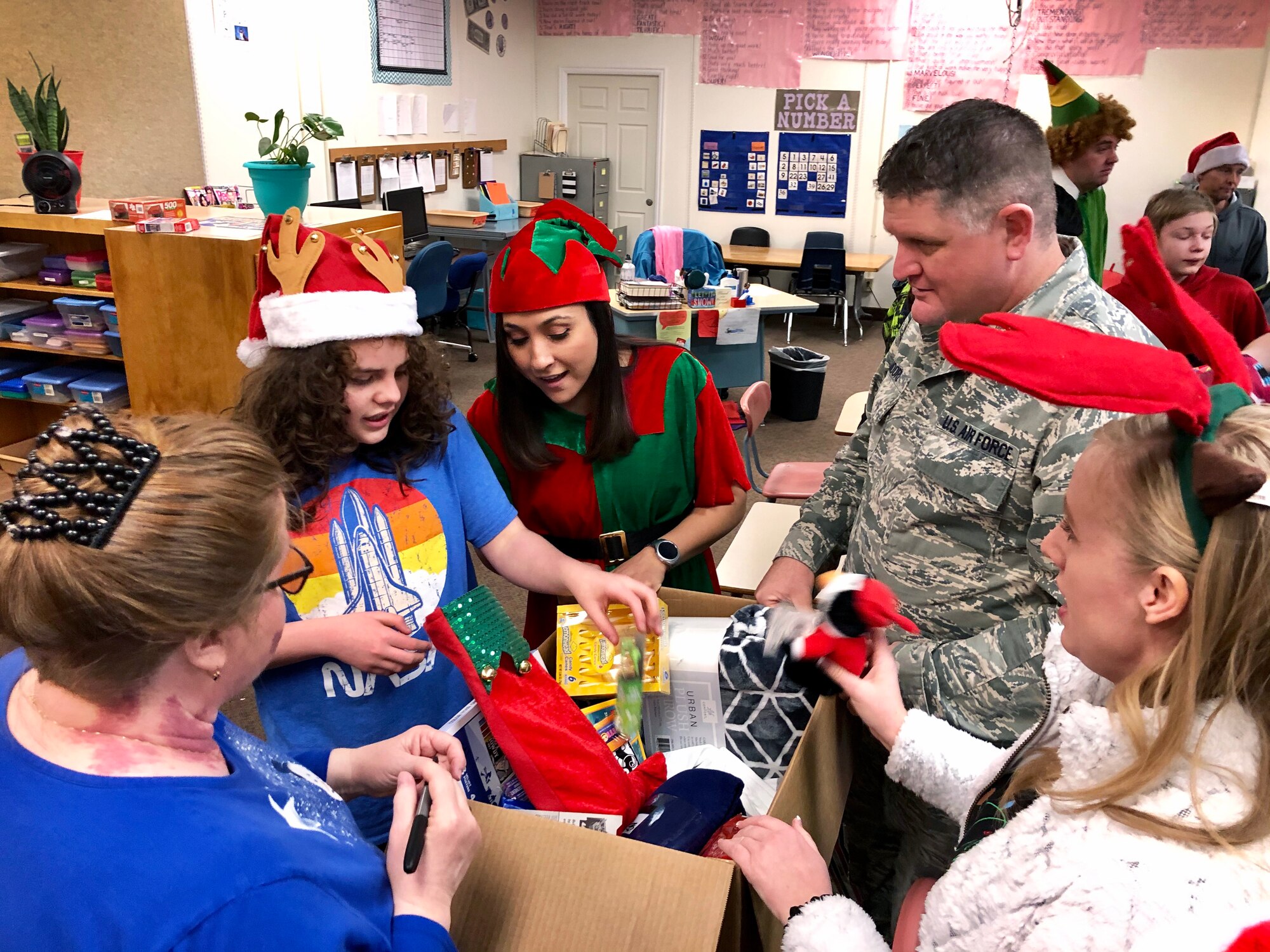 Air Force reservists from the wing’s 67th Aerial Port Squadron help Shawn unwrap gifts during a Christmas party for students with special needs at Ogden’s Mound Fort Junior High