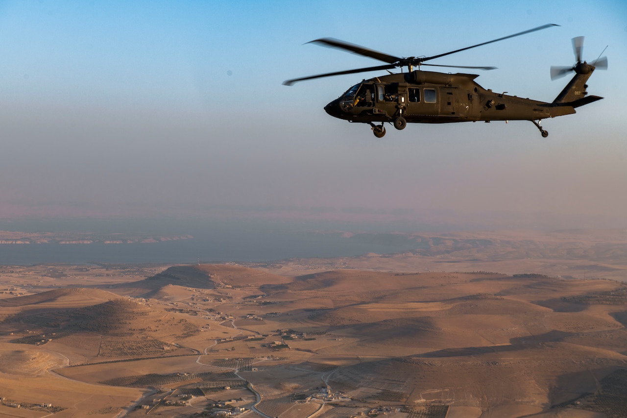 A helicopter flies over a desert.