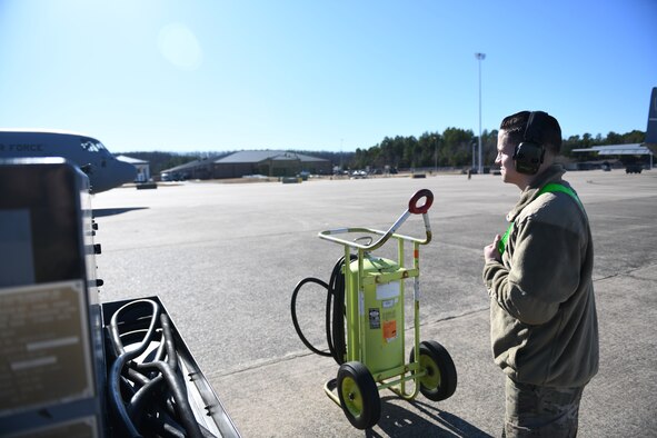 An Airman stands on the flight line while observing a pilot preparing to take off.