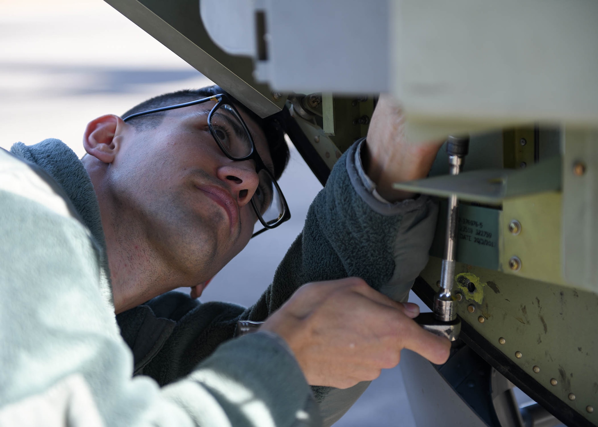 An Airman uses a tool to unscrew a bolt on a C-130J Super Hercules.