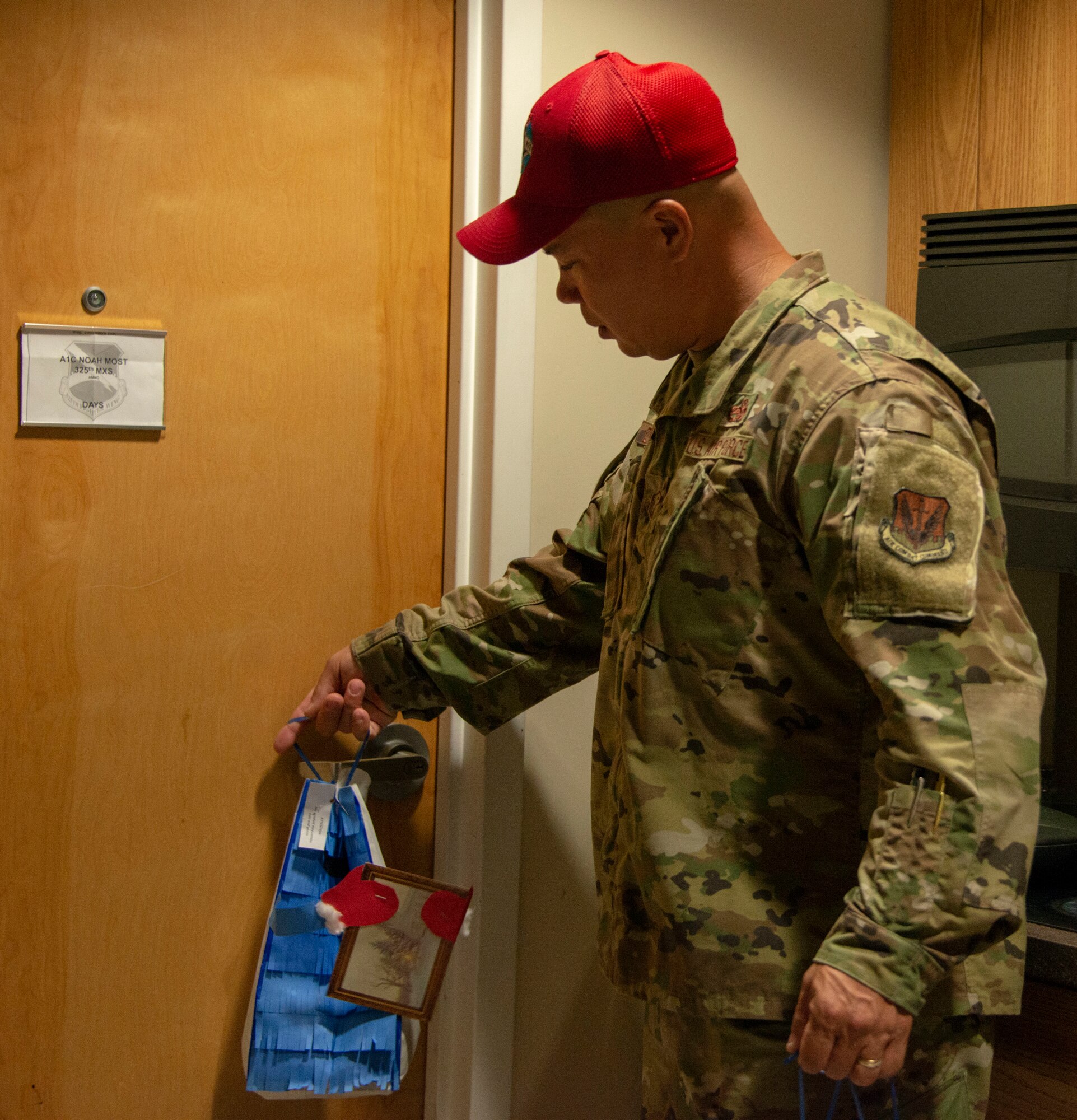 The first sergeant assigned to Detachment 1, 823rd Rapid Engineer Deployable Heavy Operational Repaid Squadron Engineer (REDHORSE) delivers a bag of homemade, donated holiday cookies to an Airman's dorm room at Tyndall Air Force Base, Florida, Dec. 9, Florida. The Tyndall First Sergeants and the Tyndall Spouses Club organized a Cookie Caper event to give sweets to the Airmen living in on base dormitories. Students at Tyndall Elementary School handmade the fun goodie bags. (U.S. Air Force photo by 2nd Lt. Kayla Fitzgerald)