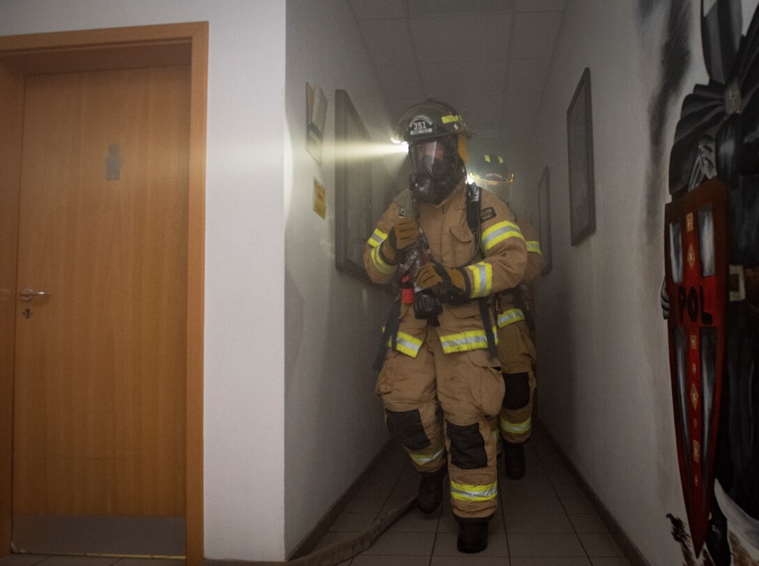 86th Civil Engineer Squadron firefighters carry a waterhose while responding to a simulated building fire during Exercise Operation Varsity 19-04 at Ramstein Air Base, Germany, Dec. 10, 2019. In addition to testing firefighter’s response time and effectiveness, the scenario tested the 86th Logistics Readiness Squadron’s ability to evacuate the builidng and secure assets against the fire.