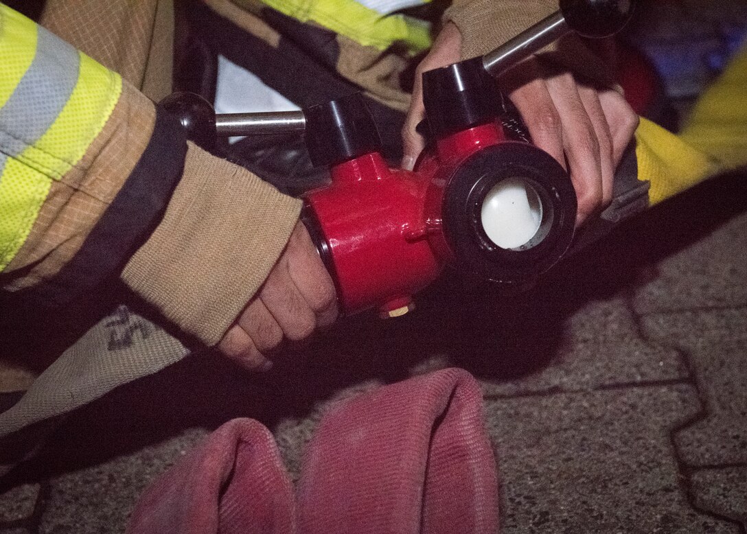 A 86th Civil Engineer Squadron firefigter connects water hoses during Exercise Operation Varsity 19-04 at Ramstein Air Base, Germany, Dec. 10, 2019. Firefighters responded to a simulated building fire after an exercerise aerial attack and were evaluated on their response.