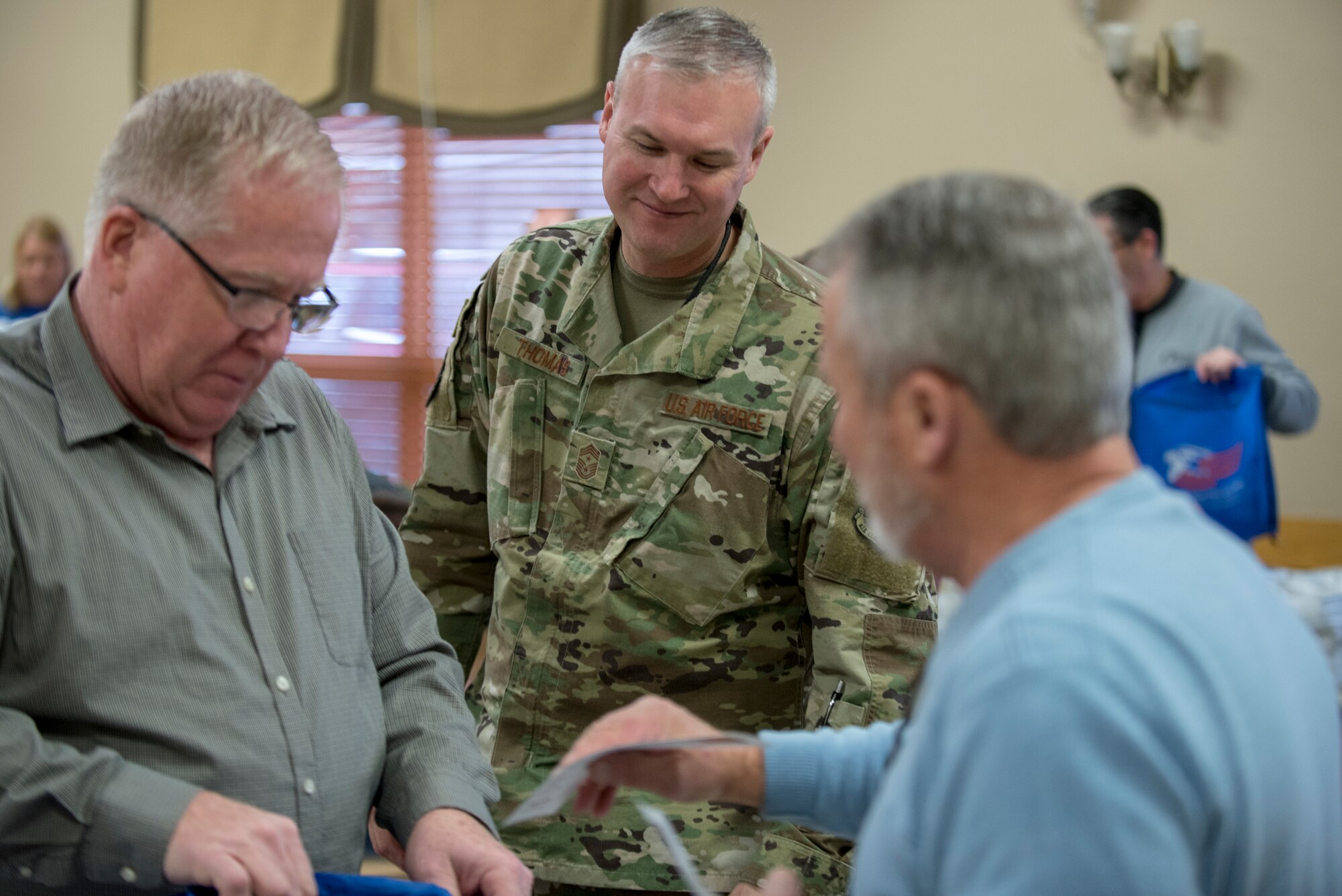 Chief Master Sgt. Brian Thomas, center, 55th Wing command chief, and members of the Bellevue Chamber of Commerce  fill holiday cheer bags Dec. 10, 2019. Members of the Bellevue Chamber of Commerce and Offutt Air Force Base leadership filled holiday cheer bags for dorm residents here.