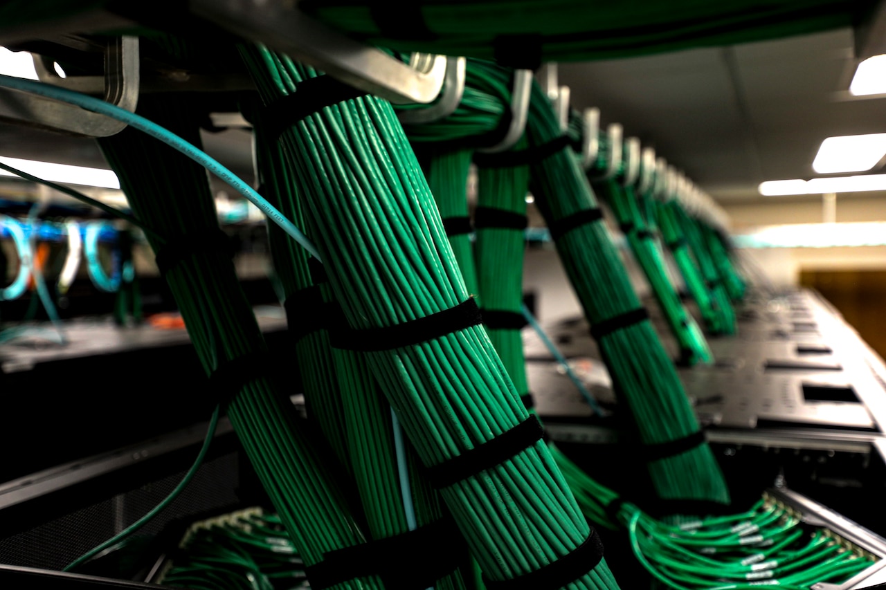 A series of bundles of green wires connected to servers.