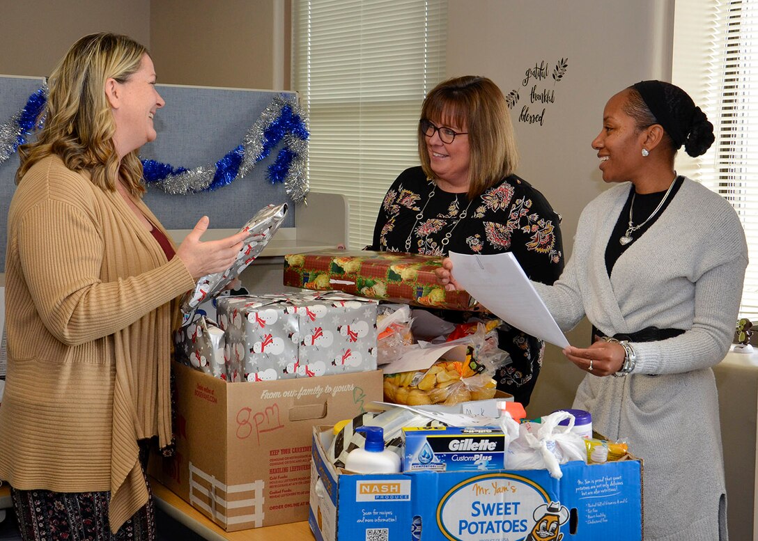 Three women check packages and a list for donation.