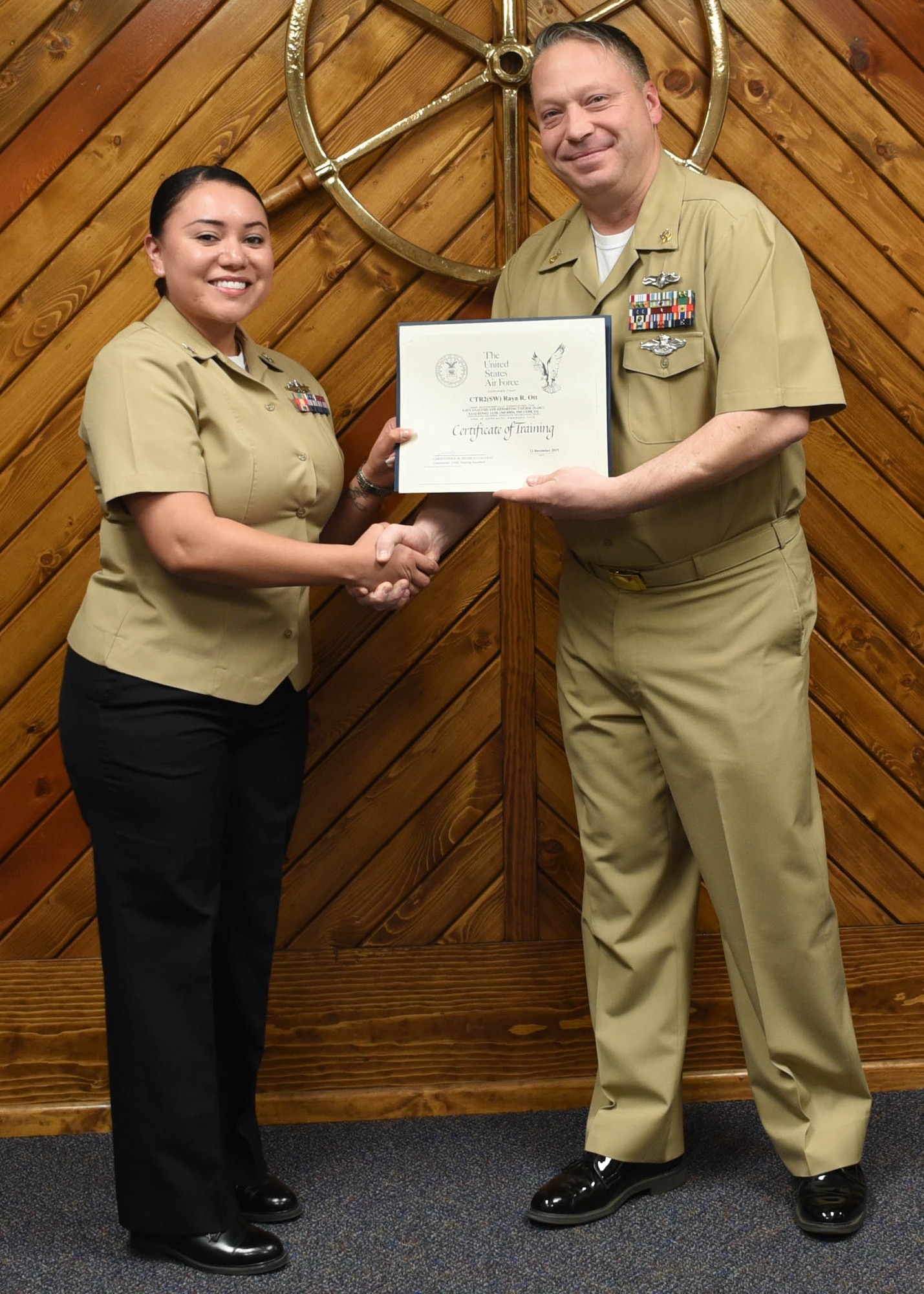 U.S. Navy Petty Officer 2nd Class Raya Ott, 316th Training Squadron cryptologic technician, receives a Letter of Appreciation from Master Chief Petty Officer Joseph Rynolds, Navy senior enlisted leader, during the Navy Analysis and Reporting course graduation ceremony at the Center for Information Warfare Training Detachment on Goodfellow Air Force Base, Texas, Dec. 12, 2019.  Ott received the award for volunteering 46 hours, which positively reflected a commitment to public service, community involvement and exemplified the highest standard of personal excellence. (U.S. Air Force photo by Airman 1st Class Abbey Rieves)