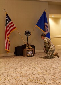 A Soldier kneels in front of a Battlefield Cross memorializing the fallen Minnesota Army National Guard Soldiers who died Dec. 5, 2019, in a UH-60 Black Hawk Helicopter crash outside St. Cloud, Minn. The memorial was posted outside a ballroom at the fiscal year 2020 Aviation Safety and Standardization Conference in Tucson, Ariz.