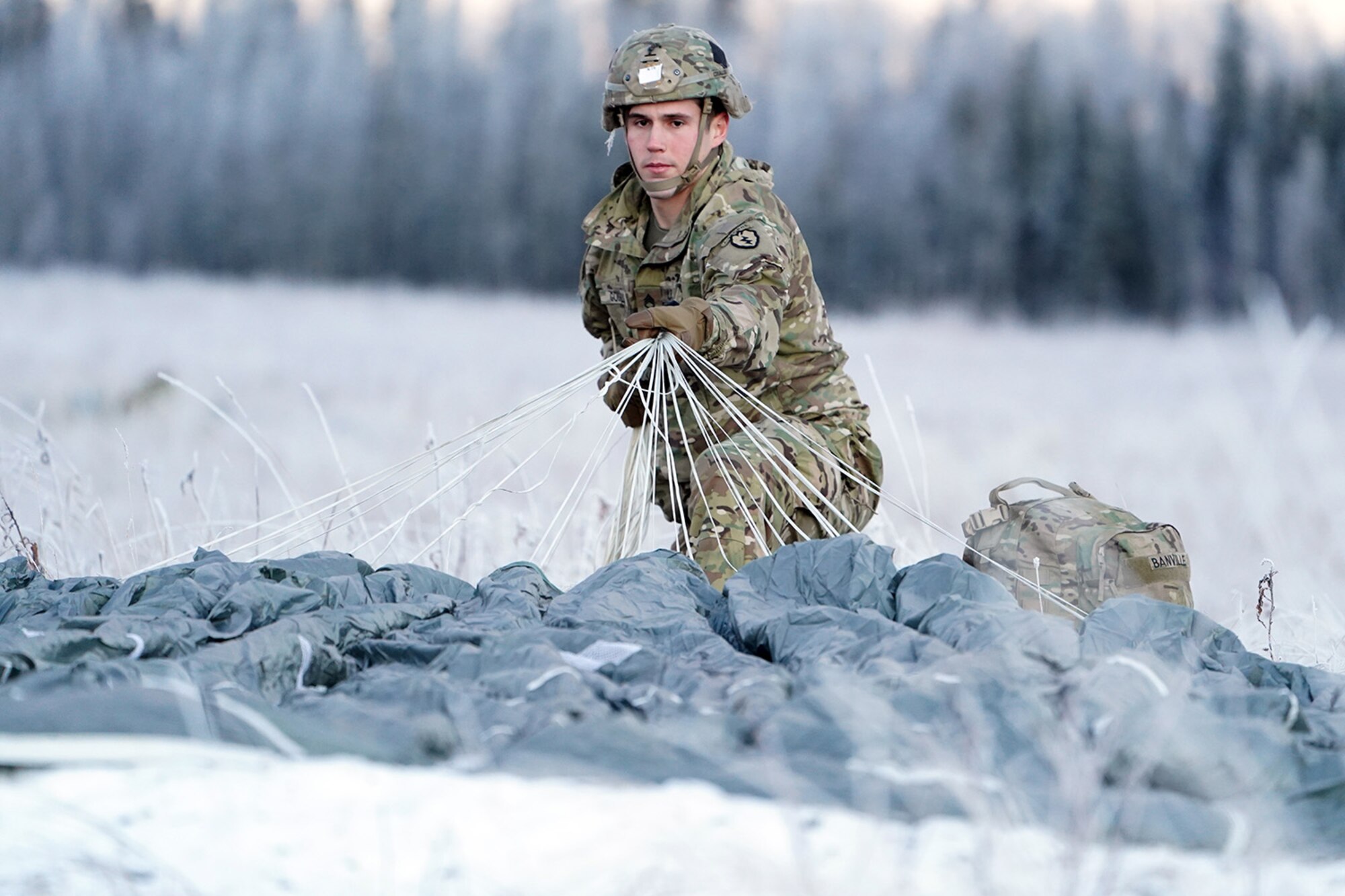 Army Staff Sgt. Joshua Couillou, a native Buford, Ga., assigned to the 1st Battalion, 501st Parachute Infantry Regiment, 4th Infantry Brigade Combat Team (Airborne), 25th Infantry Division, U.S. Army Alaska, gathers up his parachute after a jump on Malemute drop zone at Joint Base Elmendorf-Richardson, Alaska, Dec. 11, 2019. The Soldiers are part of the Army’s only Pacific airborne brigade with the ability to rapidly deploy worldwide, and are trained to conduct military operations in austere conditions.