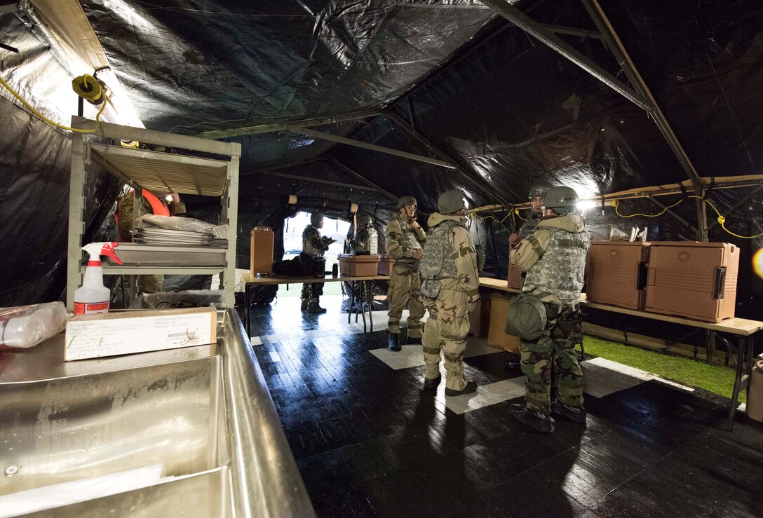 U.S. Air Force personnel assigned to the 721st Force Support Squadron prepare equipment within in a single pallet expeditionary kitchen assembled during Exercise Operation Varsity 19-04 at Ramstein Air Base, Germany, Dec. 11, 2019. They wore chemical, biological, radiological and nuclear protective training gear while assembling the kitchen to train in a simulated chemical-threat environment.