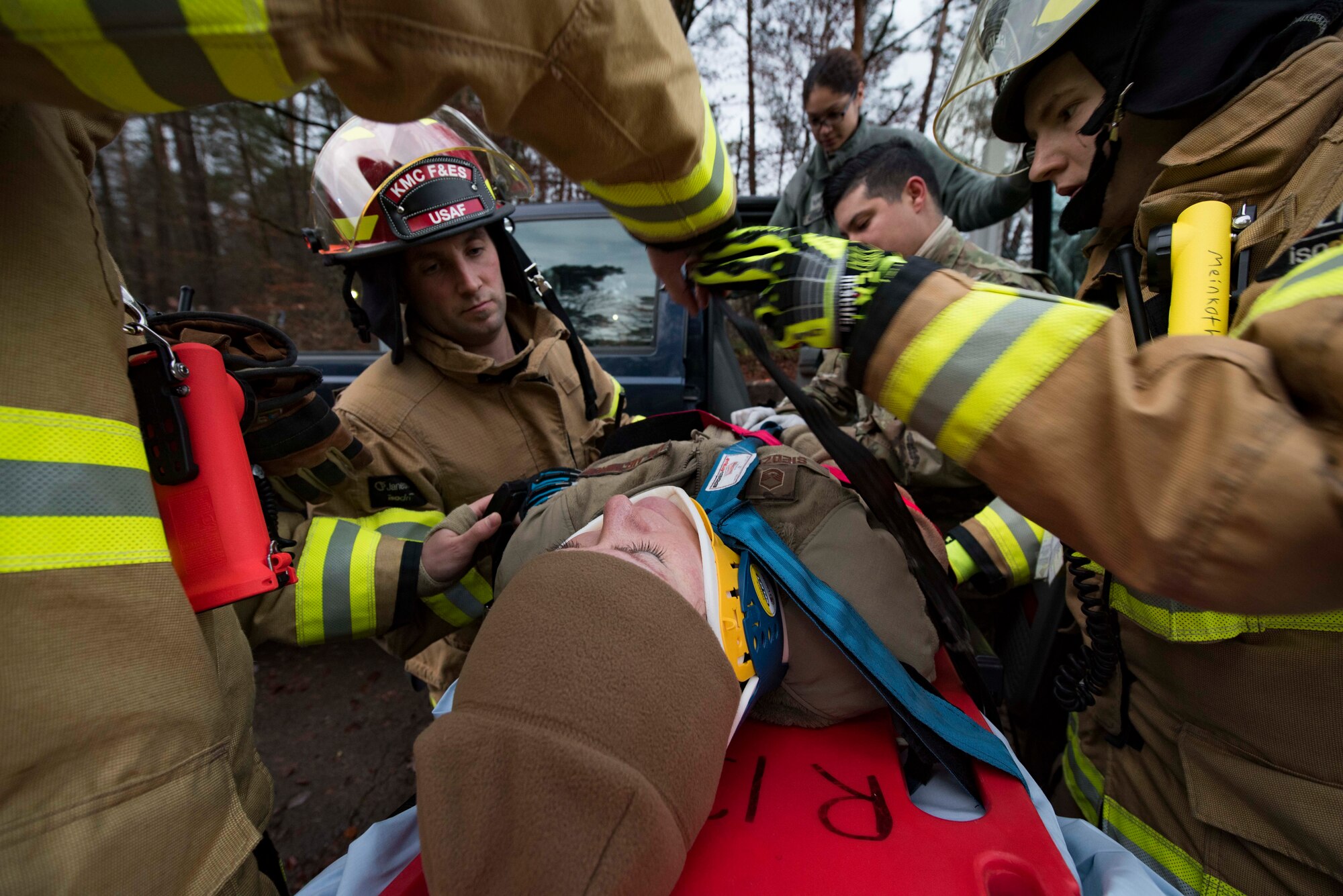 86th Civil Engineer Squadron firefighters strap an Airman playing as a car crash victim to a gurney during Exercise Operation Varsity 19-04 at Ramstein Air Base, Germany, Dec. 12, 2019. Firefighters and 86th Medical Group personnel followed their training by communicating with the victim and keeping her calm while extracting her from the vehicle and transporting her to an ambulance.