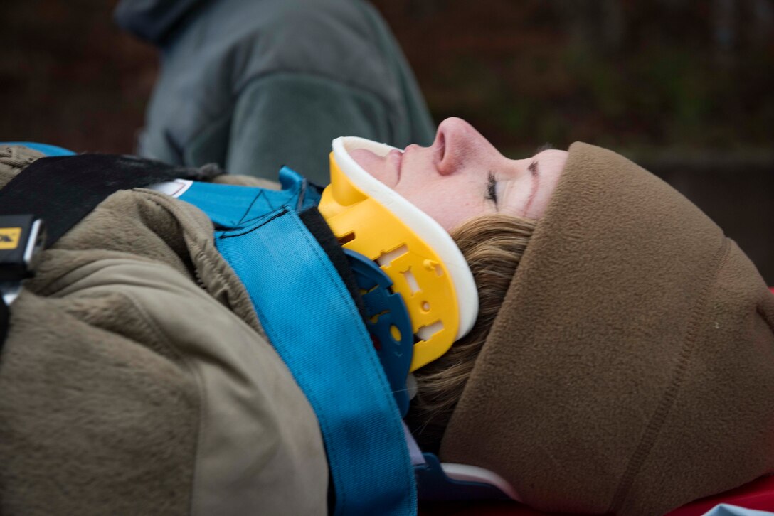 U.S. Air Force Master Sgt. Ryann Siedzek, 86th Medical Squadron radiology technician, plays the role of a car crash victim during Exercise Operation Varsity 19-04 at Ramstein Air Base, Germany, Dec. 12, 2019. Using an actor rather than a manequin to simulate a victim added realistic human responses to the scenario. Airmen assgined to the 86th Medical Group and 86th Civil Engineer squadron followed their trianing by talking Siedzek through the incident and transporiting her to an ambulance.