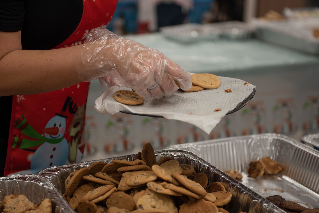 A photo of a Moody Air Force Base Airmen Cookie Drive volunteer placing cookies on a tray.