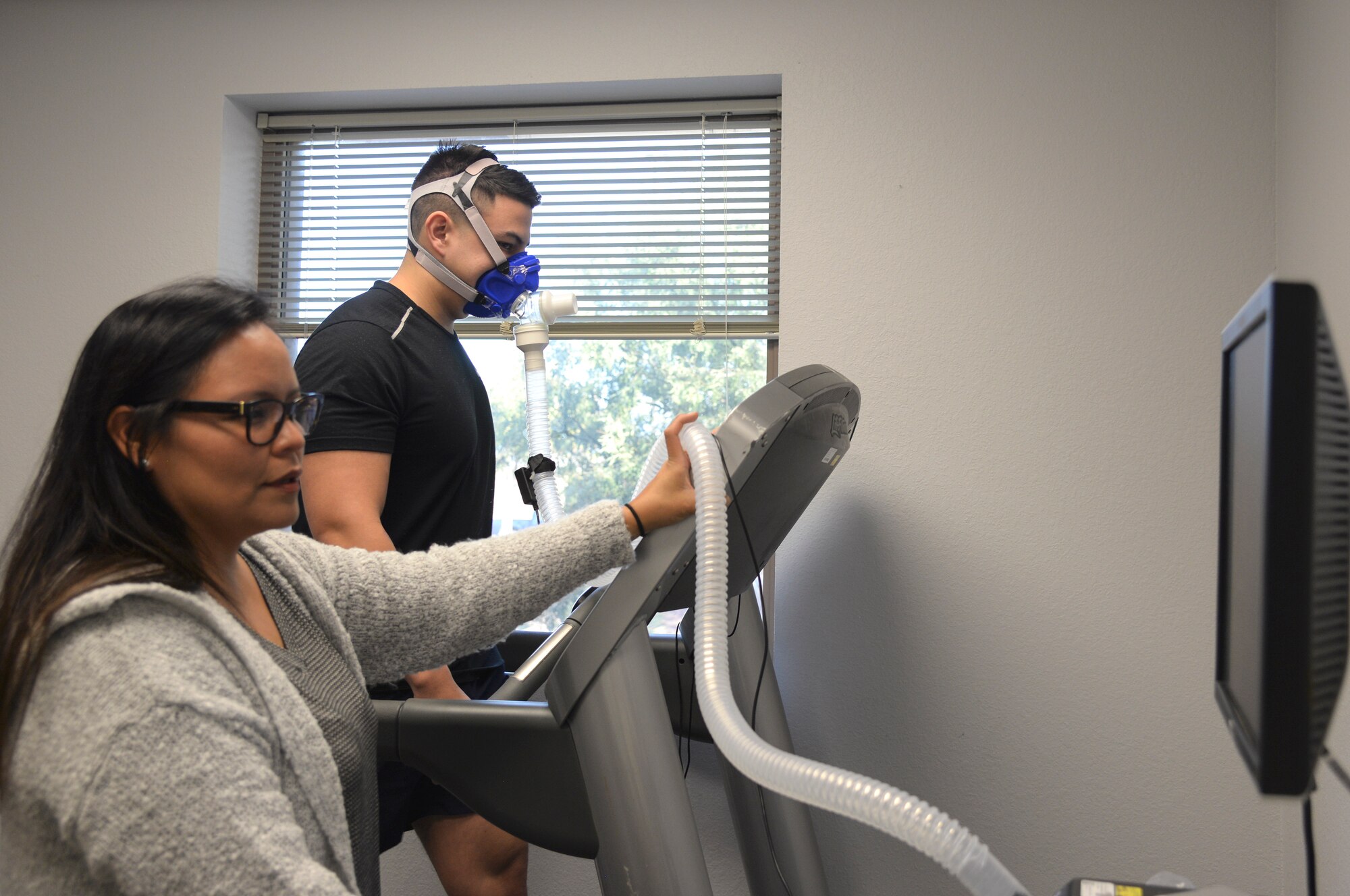 Photo of a health promotion coordinator monitoring vitals on a screen for a person walking on a treadmill