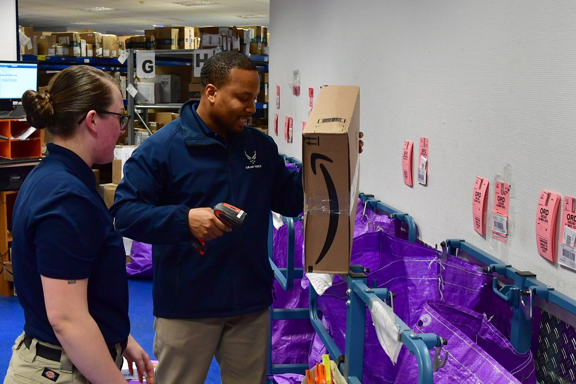 U.S. Air Force Airman 1st Class Jodi Merritt, 786th Force Support Squadron postal specialist, and Airman 1st Class Maurice Moore, 786th FSS military postal clerk, scan parcels to be shipped out from the Northside Post Office, Ramstein Air Base, Germany, Dec. 4, 2019.