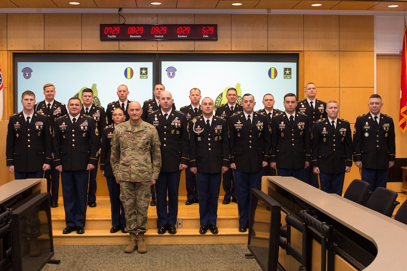 18 Army Soldiers standing on a stage after receiving their awards.