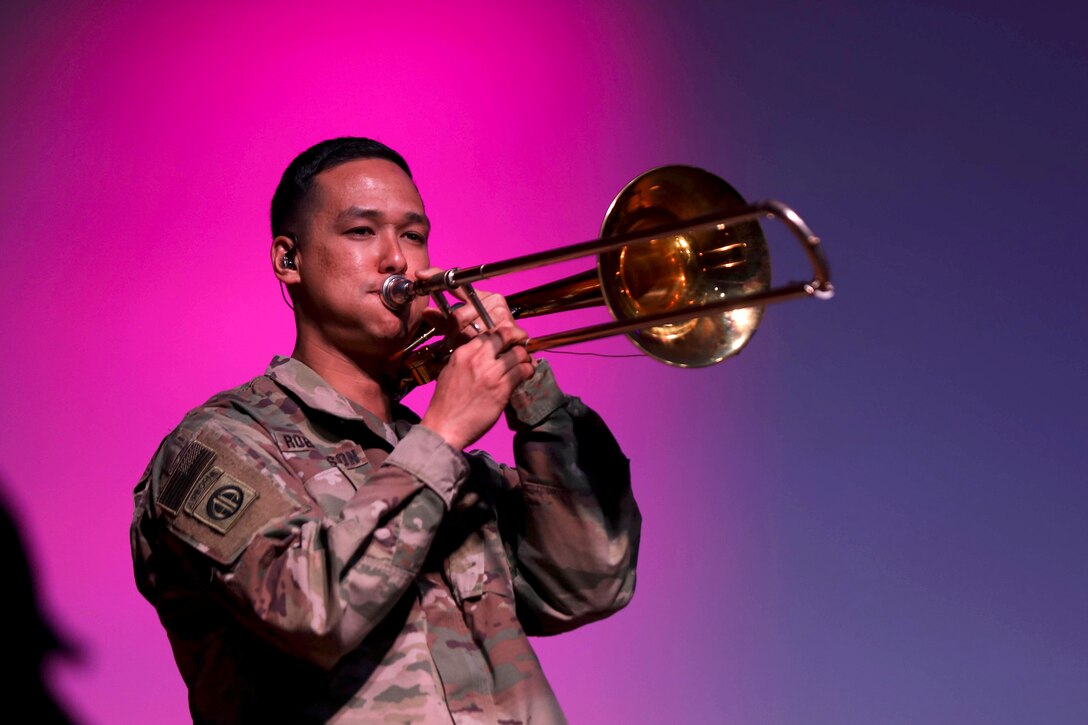 A soldier plays the trombone in uniform.