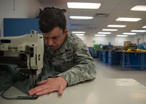 U.S. Air Force Staff Sgt. Blake Hendricks, 1st Operations Support Squadron aircrew flight equipment technician, repairs a parachute at Joint Base Langley-Eustis, Virginia, Dec. 10, 2019.