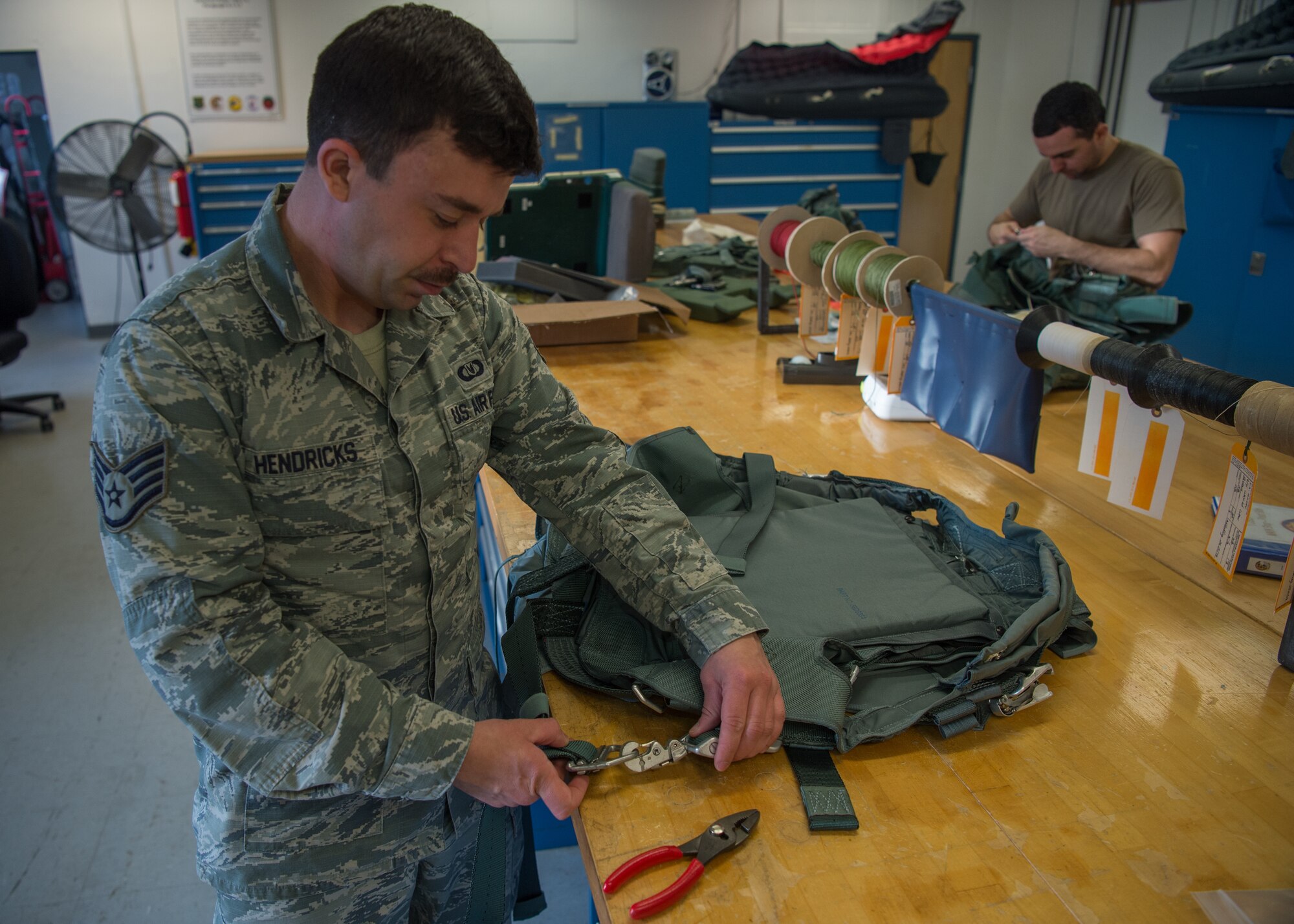 U.S. Air Force Staff Sgt. Blake Hendricks, 1st Operations Support Squadron aircrew flight equipment technician, inspects a component of a parachute being repaired at Joint Base Langley-Eustis, Virginia, Dec. 10, 2019.