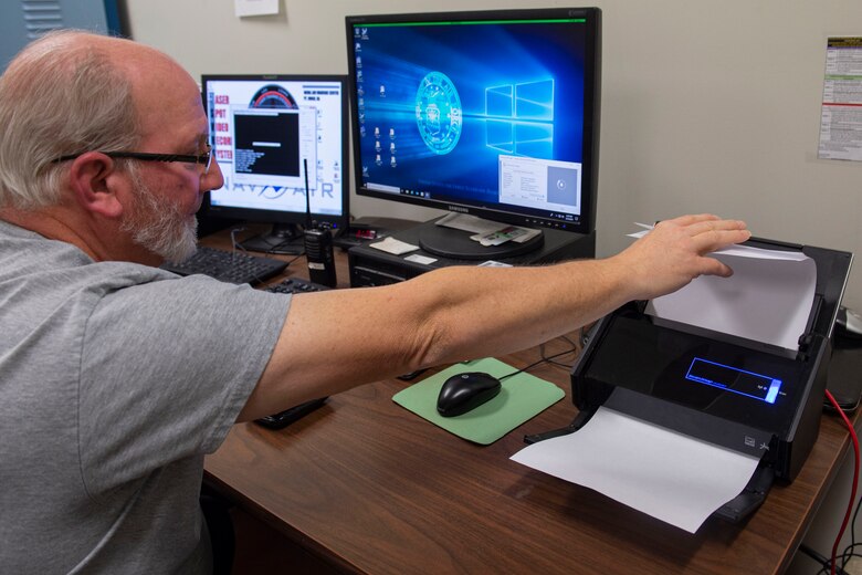 Photo of Airman scanning score documents.