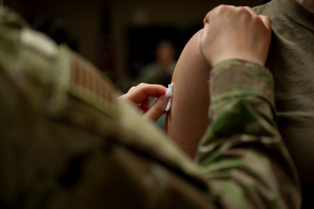 A photo of an Airman sterilizing another Airman's arm