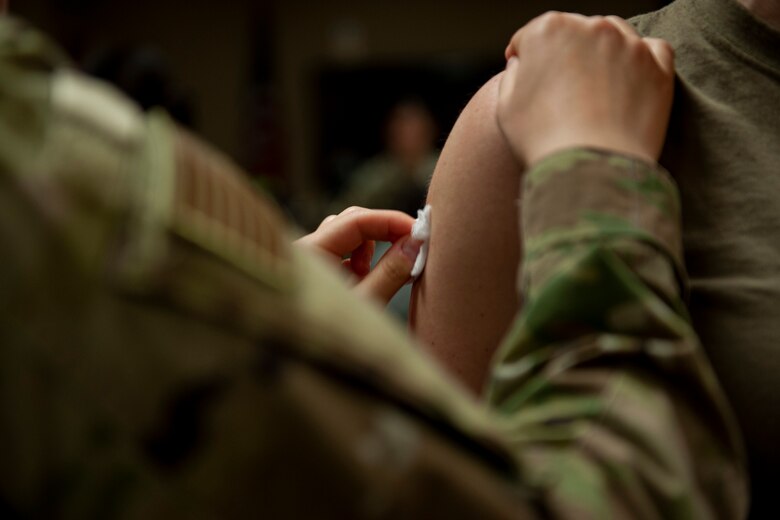 A photo of an Airman sterilizing another Airman's arm