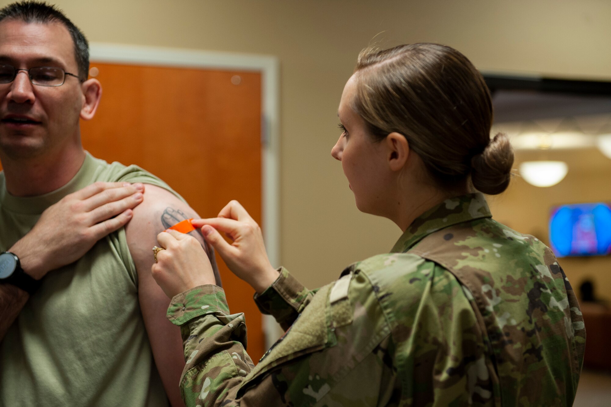 A photo of an Airman putting a bandage on a mass flu line attendee