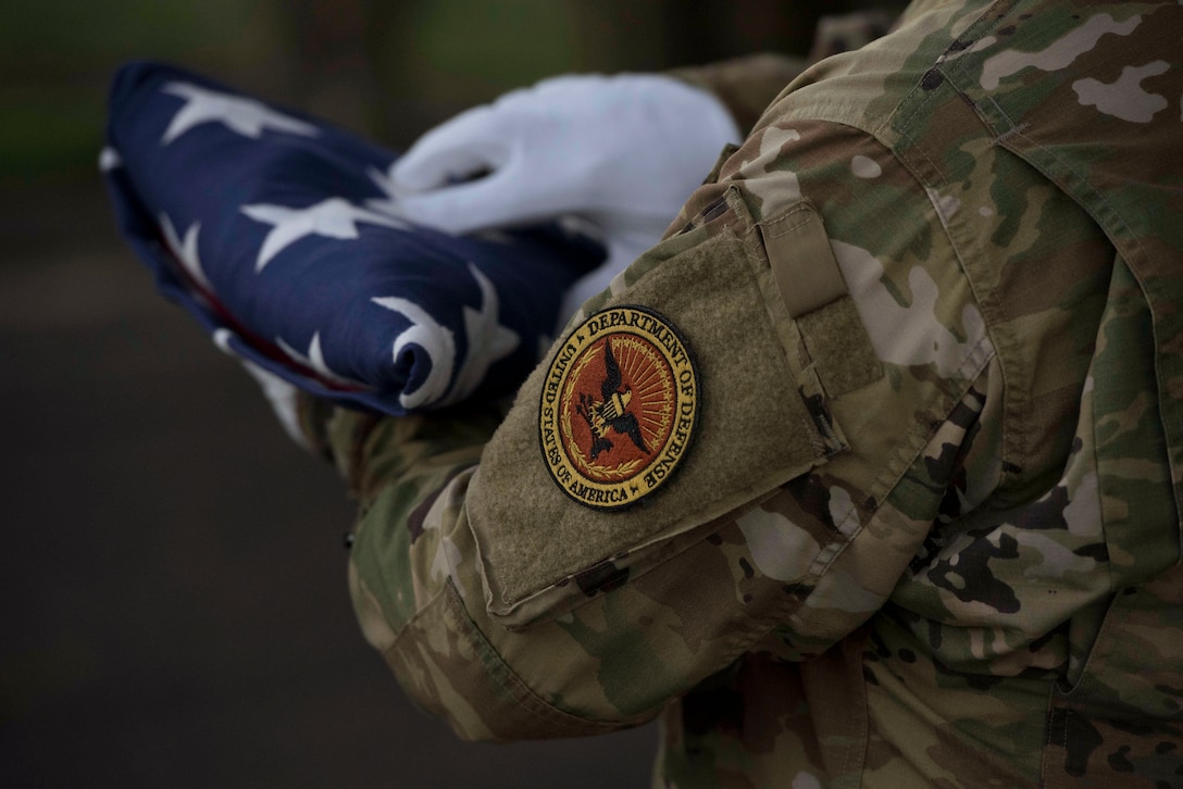 A service member holds a folded American flag.