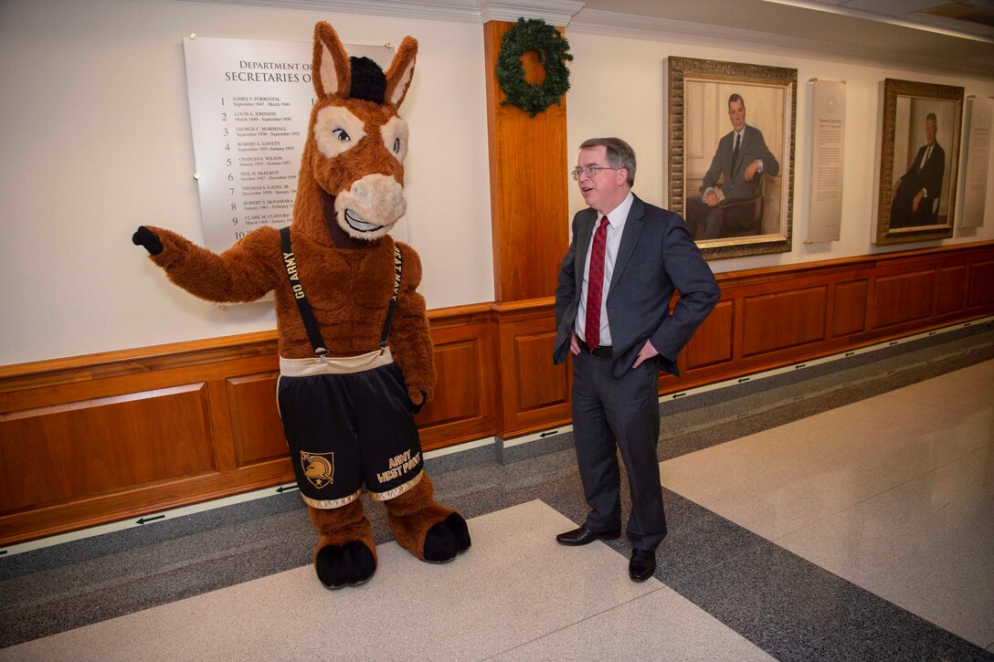 Deputy Defense Secretary David L. Norquist talks to a person dressed in a horse costume.