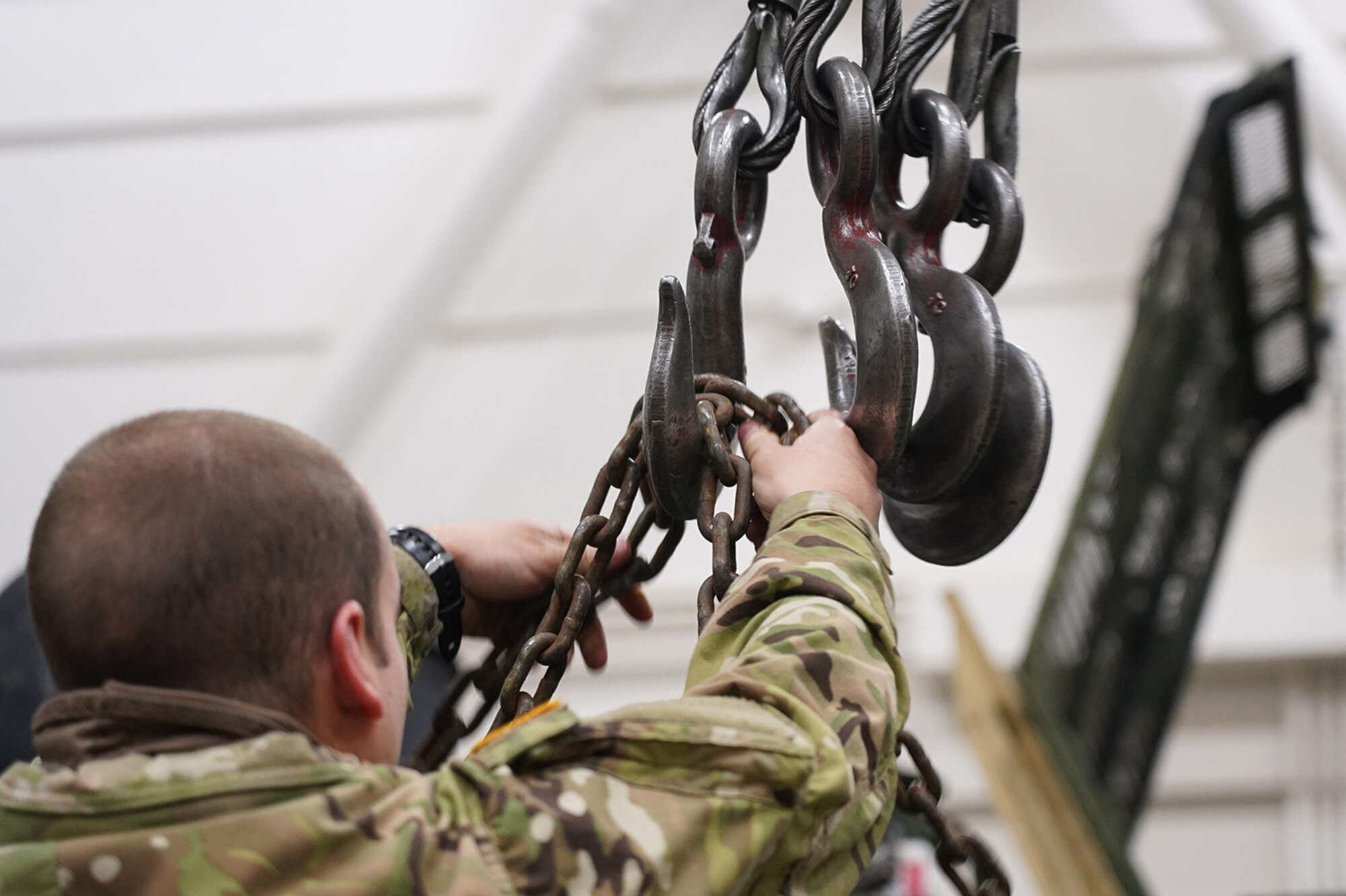 A soldier assigned to the 109th Transportation Company, 17th Combat Sustainment Support Battalion, U.S. Army Alaska, attaches chains to a hoist to move a damaged engine from an M984A2 Heavy Expanded Mobility Tactical Truck wrecker onto jack stands in his unit’s motor pool on Joint Base Elmendorf-Richardson, Alaska, Dec. 13, 2019. The M984A2 is an eight-wheel drive, diesel-powered, variant of the HEMTT used in vehicle recovery operations.