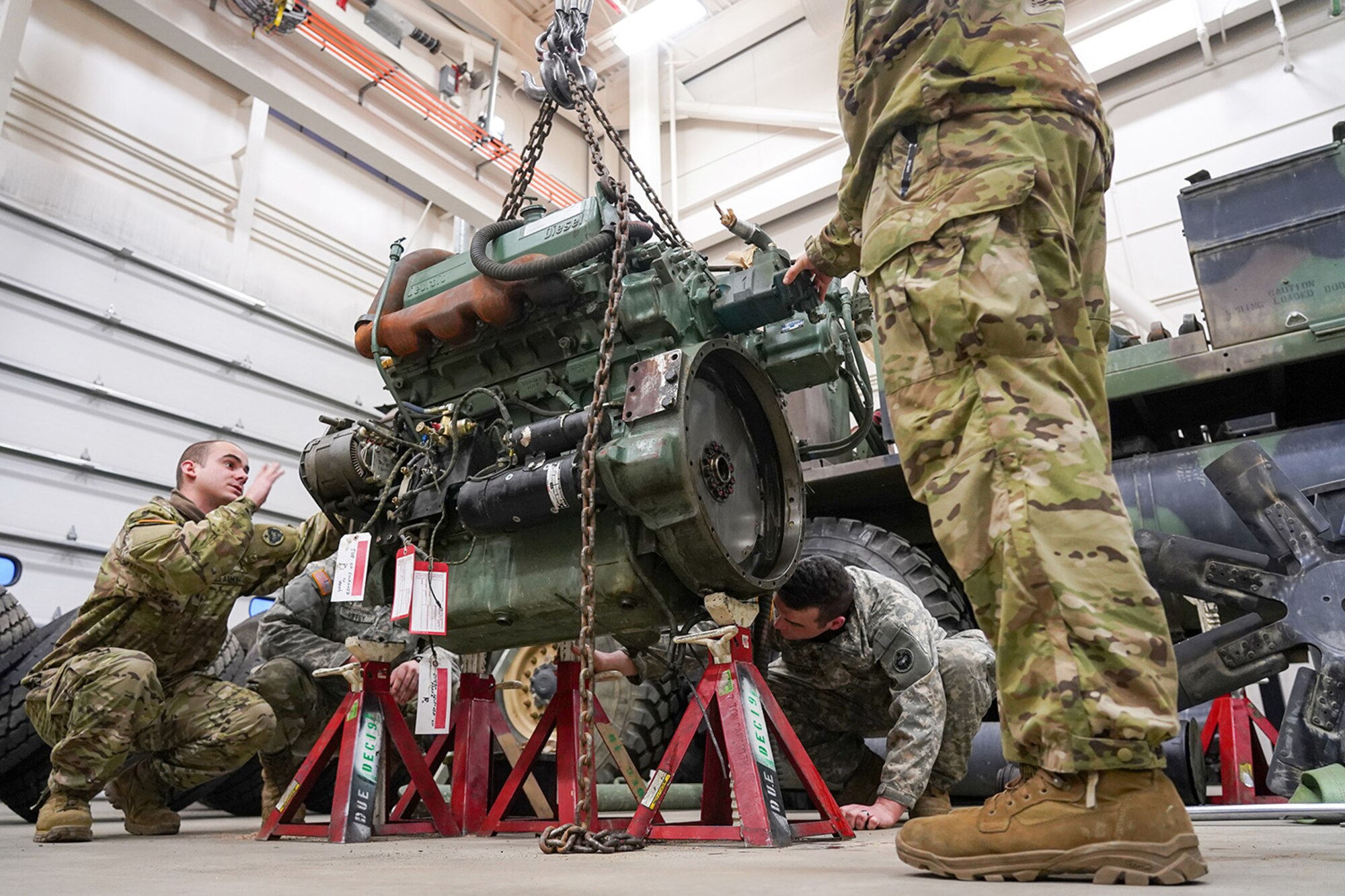 Army Sgt. Tyler Hale, a native of Wilmington, N.C., left, assigned to the 109th Transportation Company, 17th Combat Sustainment Support Battalion, U.S. Army Alaska, guides a damaged engine from an M984A2 Heavy Expanded Mobility Tactical Truck wrecker onto jack stands in his unit’s motor pool on Joint Base Elmendorf-Richardson, Alaska, Dec. 13, 2019. The M984A2 is an eight-wheel drive, diesel-powered, variant of the HEMTT used in vehicle recovery operations.